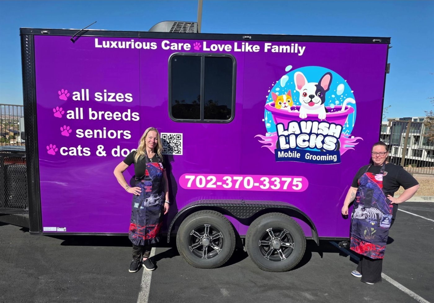 Heather and Michelle in front of the purple Lavish Licks grooming trailer